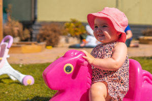 Child riding a pink play horse