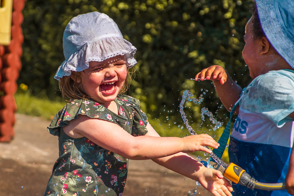 Girl playing with hose pipe and laughing